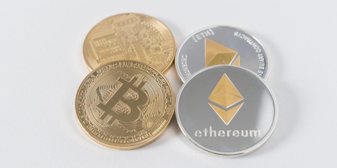 Duas moedas de bitcoin e duas de ethereum no fundo cinzento claro
